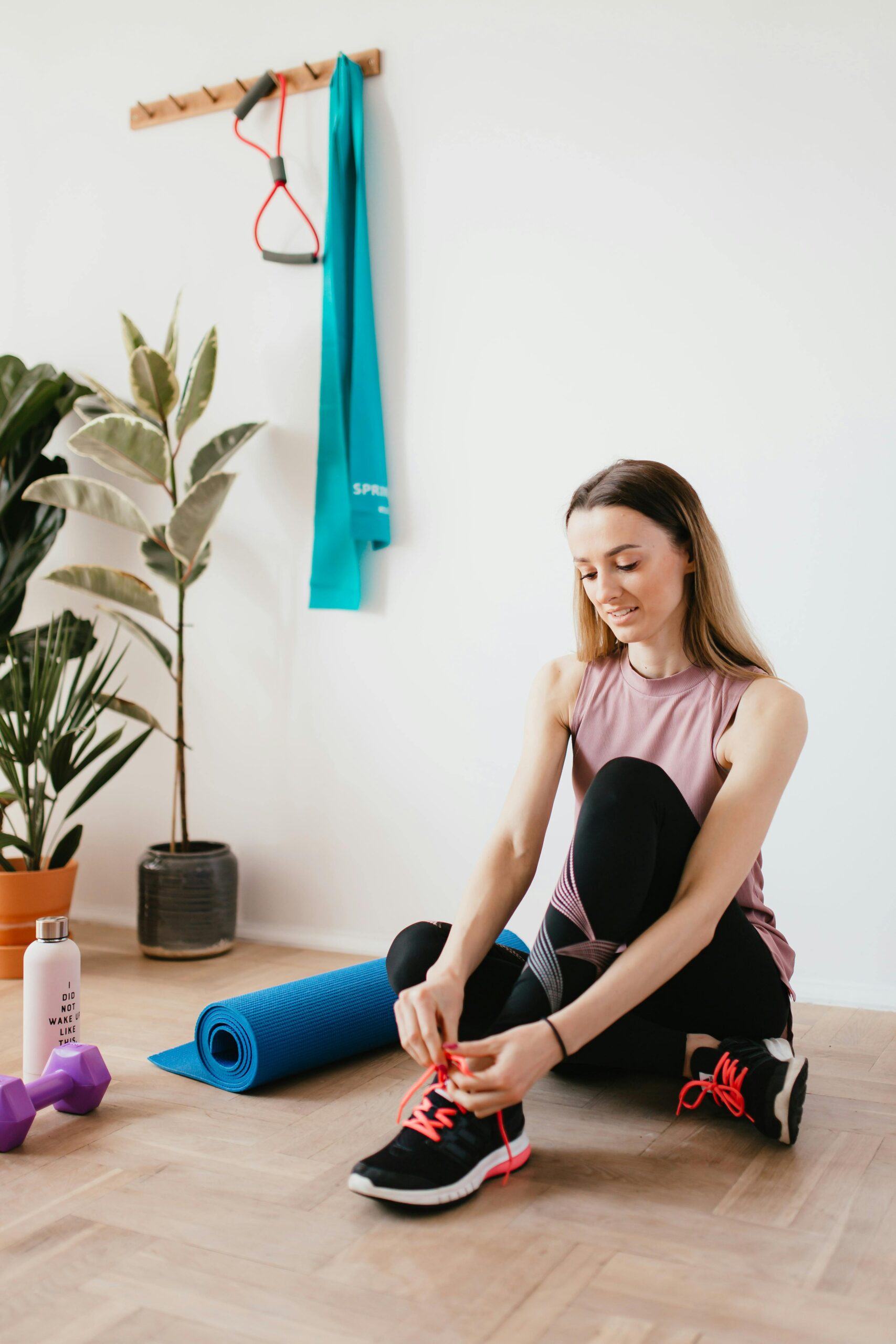 a woman tying her shoelaces on a yoga mat